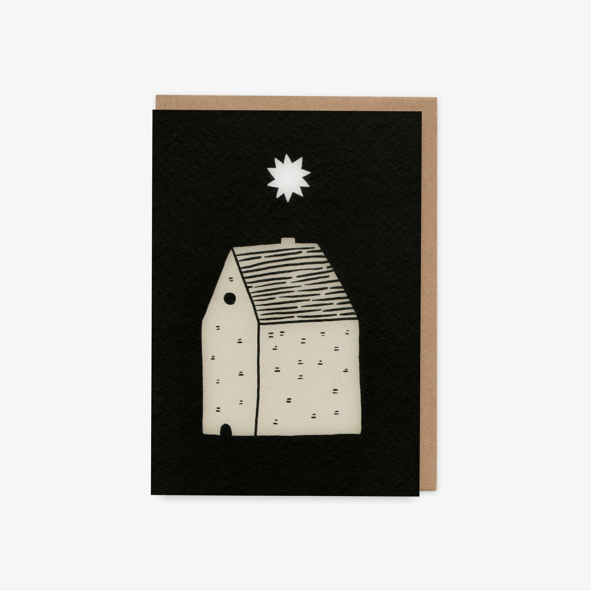 Greeting card with a black background featuring a white house and star design, with a brown envelope.